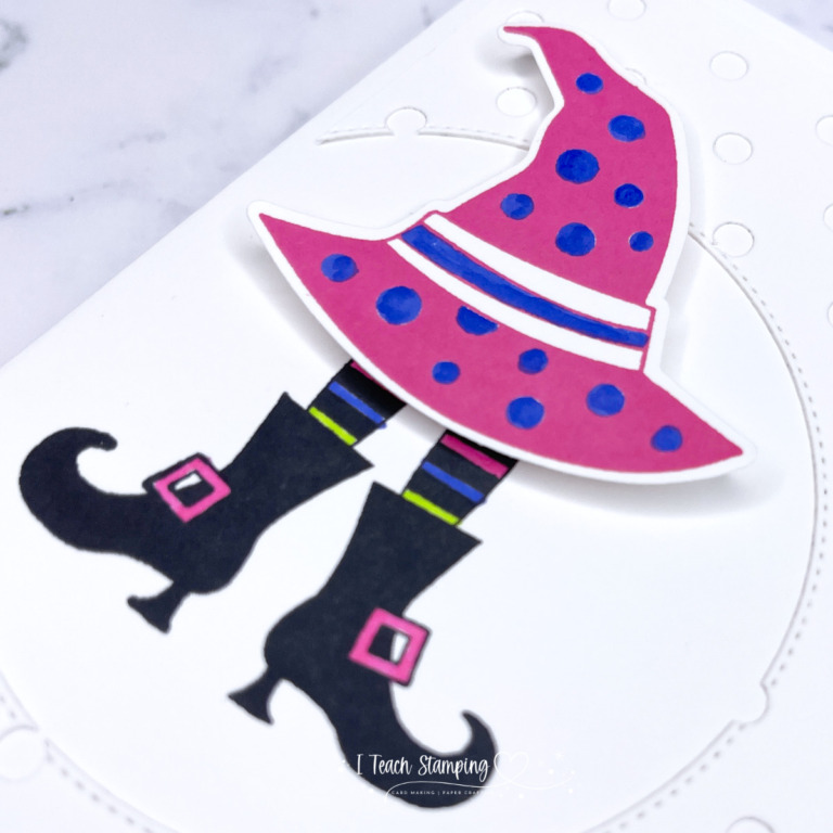 A super cute handmade Halloween card depicting a witches hat over witches boots in bright cheerful colors.